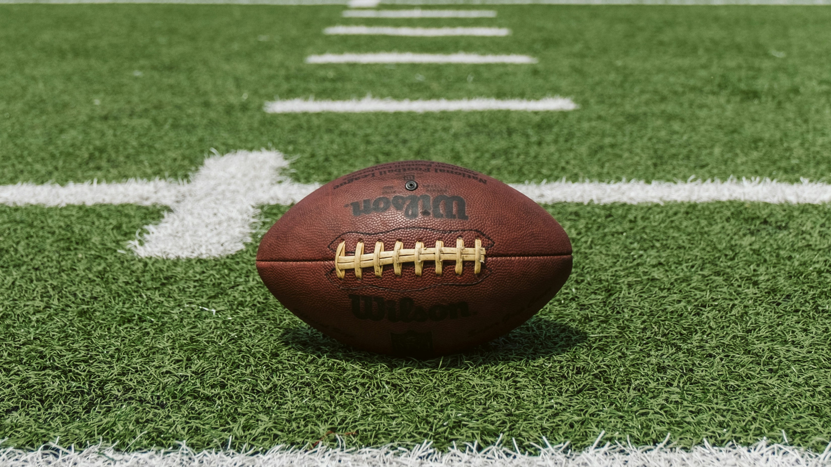 Image of an American football on an nfl field, as the cover for a blog about boot bananas giving gifts to nfl draft players