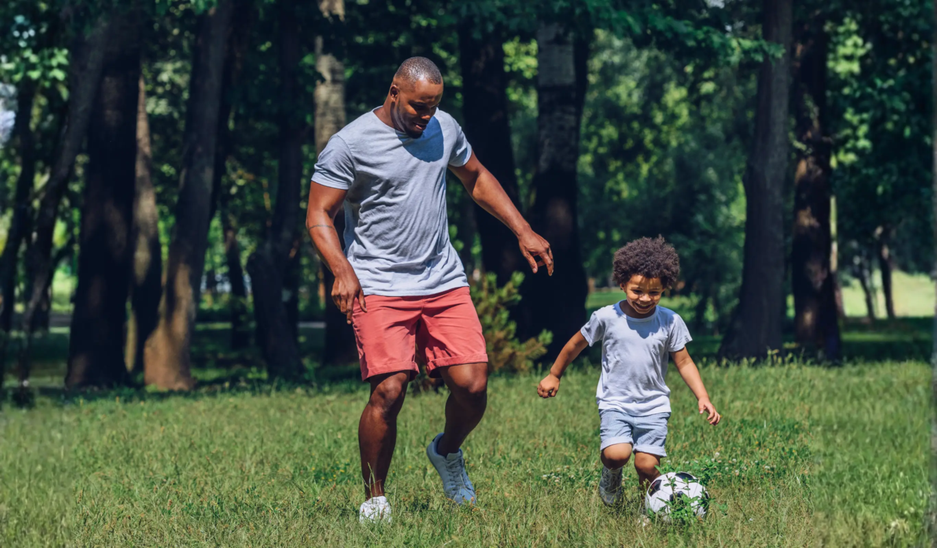 A father and son kicking a football.